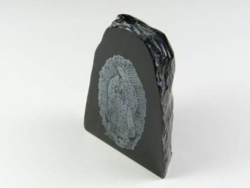 Czarny kamień z wygrawerowanym wizerunkiem Matki Boskiej na jasnym tle.