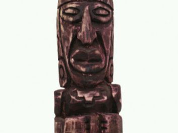 Drewniana figura przedstawiająca postać o wyrazistej, stylizowanej twarzy i złożonych dłoniach.