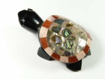 Figurka żółwia z czarną głową i kolorowym, błyszczącym pancerzem na białym tle.