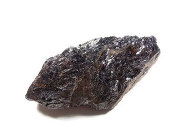 Czarny, błyszczący kawałek surowego minerału na białym tle.