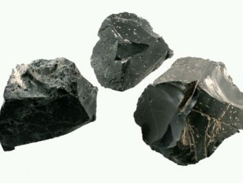 Trzy czarne bryły obsydianu na jasnym tle.