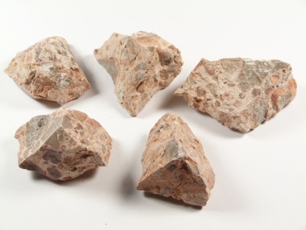 Pięć kawałków różowawego kamienia na białym tle.