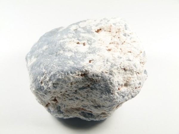 Szaro-biały, chropowaty kamień na białym tle, widoczna nierówna powierzchnia.