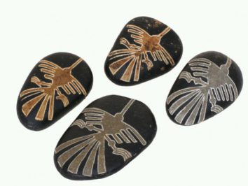 Cztery czarne kamienie z wygrawerowanym wzorem ptaka w stylu rysunków z Nazca.