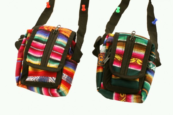 Dwie kolorowe torebki na ramię z etnicznym wzorem wiszą na haczykach.