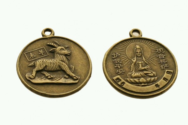 Dwa okrągłe medaliony z brązu z wizerunkiem kozy i postacią buddyjską oraz chińskimi napisami.