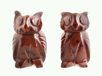 Dwa figurki sowy z czerwonego kamienia ustawione obok siebie na jasnym tle.