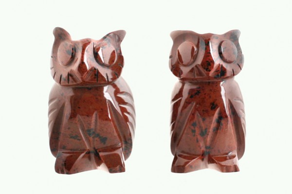 Dwa figurki sowy z czerwonego kamienia ustawione obok siebie na jasnym tle.