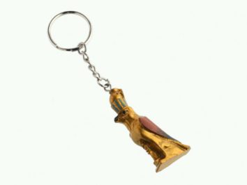 Breloczek z figurką złotego ptaka z egipskimi motywami na białym tle.