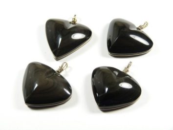 Cztery czarne wiszące zawieszki w kształcie serca leżą na białym tle.