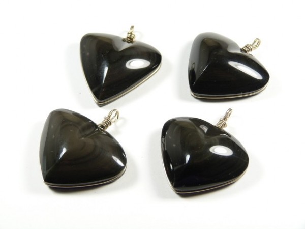 Cztery czarne wiszące zawieszki w kształcie serca leżą na białym tle.