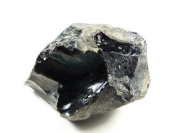 Czarny, błyszczący okaz obsydianu na białym tle.