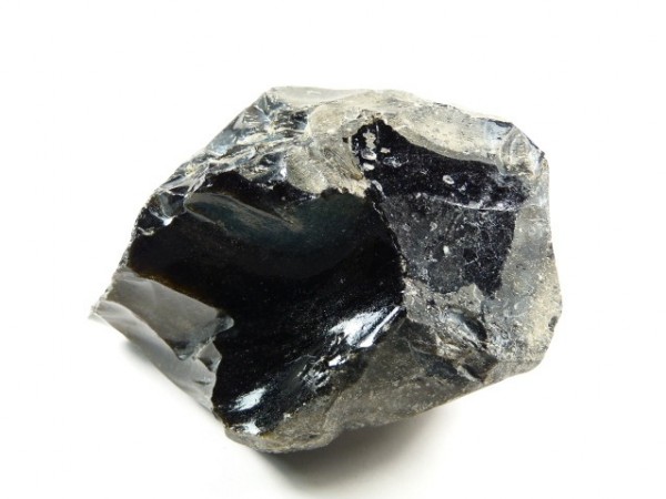 Czarny, błyszczący okaz obsydianu na białym tle.