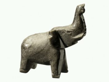 Kamienna figurka słonia z uniesioną trąbą na jasnym tle.