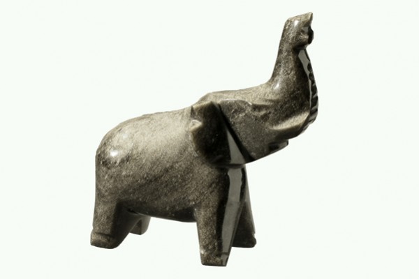 Kamienna figurka słonia z uniesioną trąbą na jasnym tle.