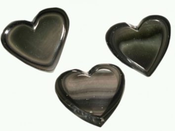 Trzy czarne kamienie w kształcie serca na jasnym tle.