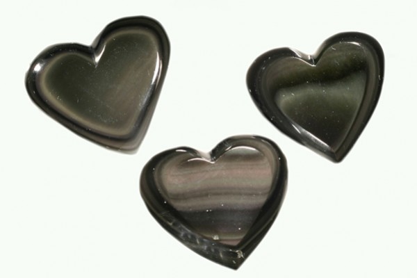 Trzy czarne kamienie w kształcie serca na jasnym tle.