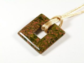 Kwadratowy wisiorek z kamienia w odcieniach zieleni i różu na jasnym sznurku.