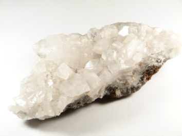 Bryła białego kryształu kalcytu na jasnym tle.