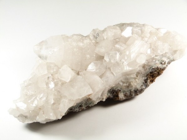 Bryła białego kryształu kalcytu na jasnym tle.