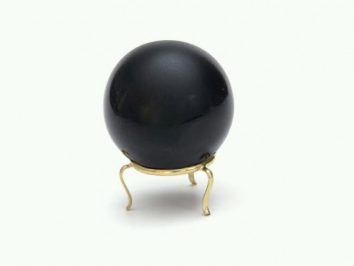 Czarna kula na złotym stojaku na białym tle.