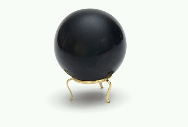 Czarna kula do wróżenia ustawiona na złotym stojaku, na białym tle.
