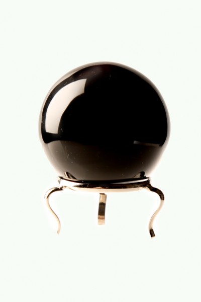 Czarna kula wróżbiarska z obsydianu na metalowym stojaku na jasnym tle.