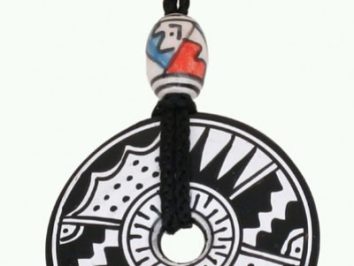 Czarnobiały wisiorek z geometrycznym wzorem, zawieszony na sznurku z ozdobnym koralikiem.