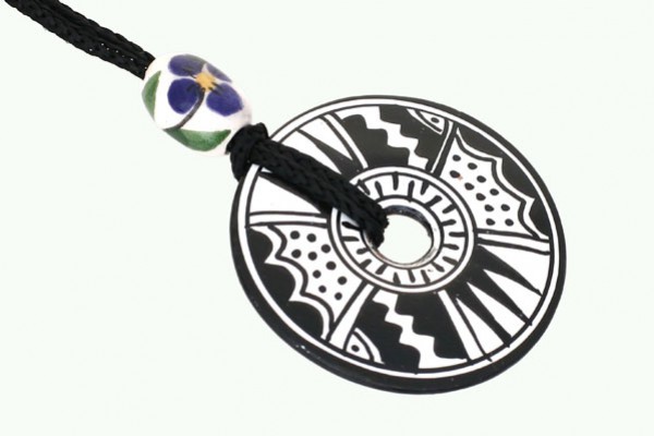 Czarnobiały, okrągły wisiorek z geometrycznym wzorem na czarnym sznurku z ozdobnym koralikiem.