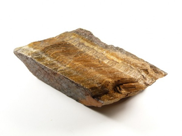 Brązowy kamień tygrysie oko na białym tle, widoczna charakterystyczna pasiasta struktura.