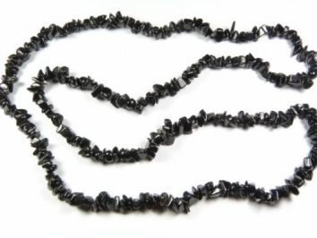 Czarny naszyjnik z nieregularnych kamieni nawleczonych na sznurek, ułożony na białym tle.