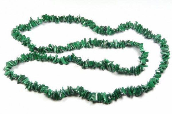 Naszyjnik z zielonych, nieregularnych kamieni ułożony na białym tle.
