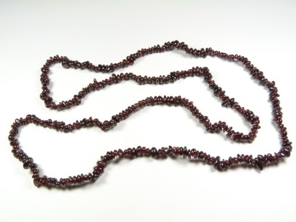 Naszyjnik z ciemnoczerwonych kamieni, ułożony na białym tle.