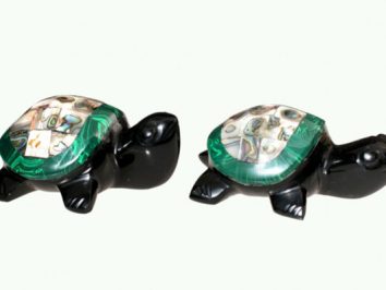 Dwie czarne figurki żółwi z kolorowymi skorupami ustawione obok siebie na białym tle.