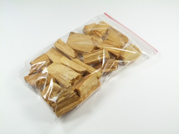Kawałki drewna w plastikowym woreczku strunowym na białym tle.