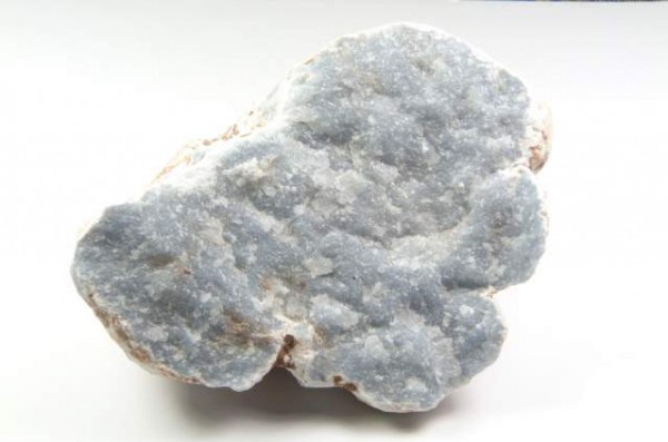 Szaro-niebieski minerał chalcedon na białym tle, widoczna jego ziarnista struktura.