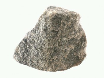 Awenturyn niebieski - kamień naturalny, surowy, nieszlifowany. Szary, nieregularny kamień na jasnym tle.