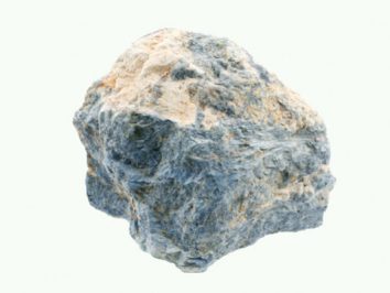 Dumortieryt - kamień naturalny, surowy, nieszlifowany. Szaro-niebieski kamień o chropowatej powierzchni na jasnym tle.