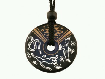 Czarny wisiorek z motywami zwierząt i ornamentów, zawieszony na czarnym sznurku.