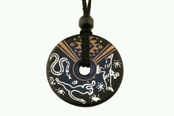 Czarny wisiorek z motywami zwierząt i ornamentów, zawieszony na czarnym sznurku.