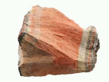 Celestobaryt - kamień naturalny, surowy, nieszlifowany. Różowy minerał z widocznymi warstwami, na jasnym tle.