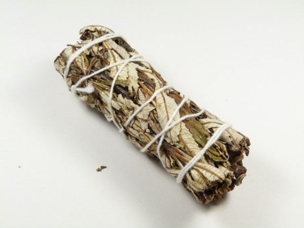 Zwinięta wiązka suszonej szałwii obwiązana białym sznurkiem, na białym tle.