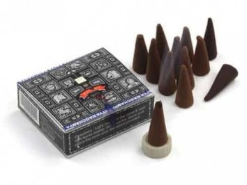 Stożki kadzidełek i pudełko z ozdobną grafiką na białym tle.