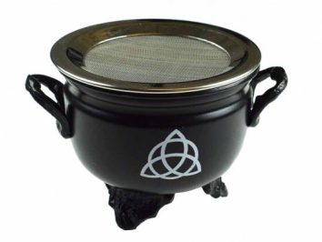 Czarny kociołek z sitkiem i symbolem triquetry na boku, stojący na trzech nóżkach.