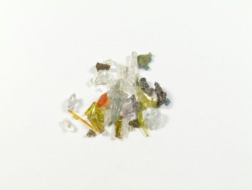 Stos kolorowych odłamków szkła na białym tle.