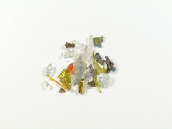 Stos kolorowych odłamków szkła na białym tle.