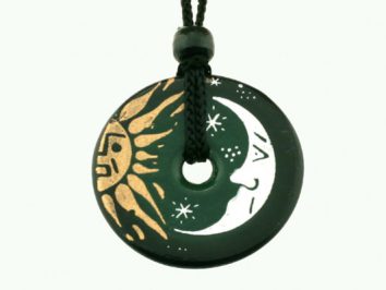 Czarny okrągły wisiorek z rysunkami słońca i księżyca, zawieszony na czarnym sznurku.