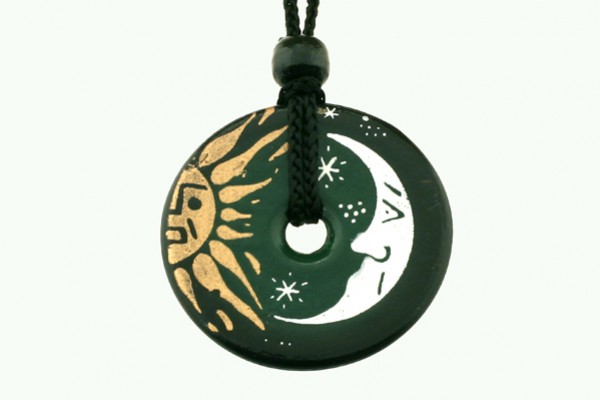 Czarny okrągły wisiorek z rysunkami słońca i księżyca, zawieszony na czarnym sznurku.