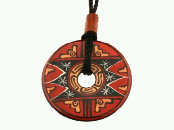 Okrągły wisiorek z czerwonym wzorem etnicznym zawieszony na czarnym sznurku.