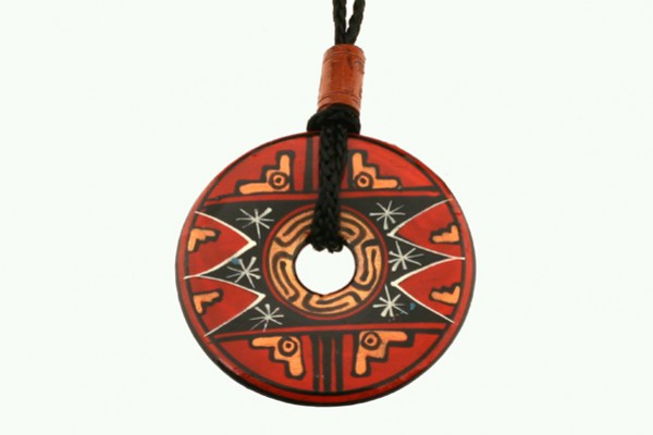 Okrągły wisiorek z czerwonym wzorem etnicznym zawieszony na czarnym sznurku.